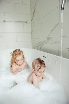 little brother and sister bathing in a foam bath