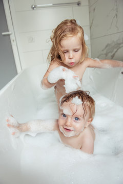little brother and sister bathing in a foam bath