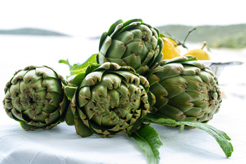 Obraz premium Cooking with fresh green artichokes heads, tasty vegetarian food, on open kitchen with sea view