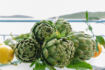 Obraz premium Cooking with fresh green artichokes heads, tasty vegetarian food, on open kitchen with sea view