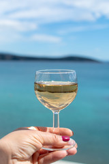 Woman hand with one glass of wine and blue sea view