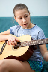 Teenage Caucasian girl tune up acoustic guitar in home