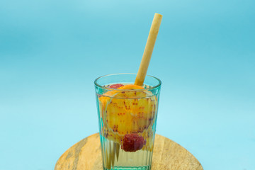 Drinking glass with blood orange and red fruits on a wooden board, insulated on a blue background. Healthy food concept.