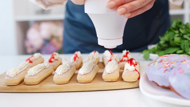 Professional baker woman arms applying appetizing sweety sause on pastry. 4k Dragon RED camera