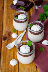 Traditional Italian dessert panna cotta with chocolate sauce and crispy meringue in glass jars. Dessert for Valentine's Day or Women's Day. Vertical orientation. Close up.