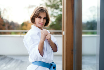 A young woman practising karate outdoors on terrace. © Halfpoint
