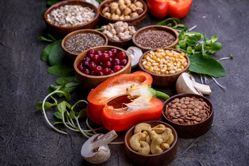 Superfoods, microgreens, nuts, berries, vegetables, grains on dark background, healthy eating.
