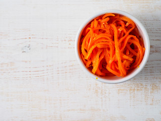 Korean carrot in the bowl on white wooden background.