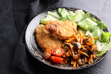 Concept of Russian cuisine. Fried chicken with mushrooms with lettuce leaves on a dark background. Home dinner on the grill. Background image, copy space