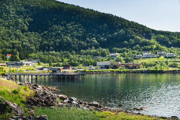 Fototapeta premium Bogen village in Nordland county, Norway. Summer beautiful Norwegian nature, landscape with old pier, fjord and sunny coastline
