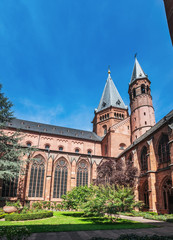 Fototapeta na wymiar Mainz Cathedral with beautiful garden under blue cloudy sky, located in Old Town of Mainz, Germany. Red church bell towers.
