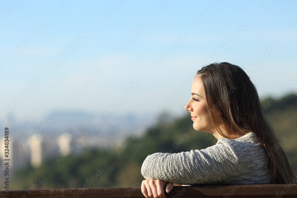 Wall mural satisfied woman contemplating views on a bench - Wall murals