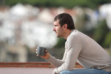 Obraz premium Serious man sitting on a bench holding coffee cup