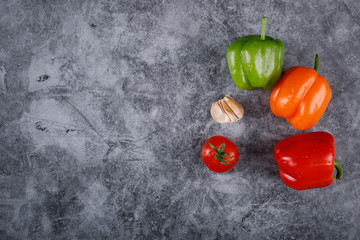 Colorful peppers, garlic and tomato on the right corner of a blue background.