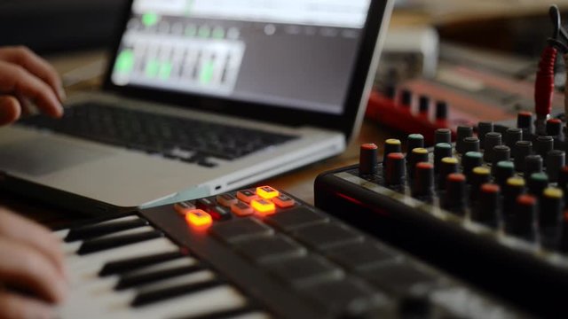 Music production in a studio, preparing a music stream,  a musician working with keybord, computer and mixer