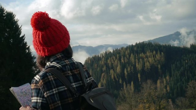 Hipster woman with map in the mountains walking in Austrian Alps. Tourism, sports, hipster, lifestyle concept.