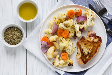 Turkey steak and vegetables cauliflower onion carrots baked in the oven on a white plate, olive oil and herbs and spices. Concept spring diet menu. Top view, flat lay
