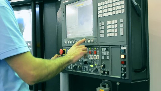 Person works behind the control panel of the production machine at the factory