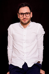 Portrait of a handsome guy on black background. Stylish pose with glasses.