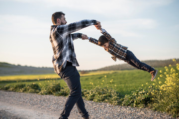 Spinning father grabbing his son with his arms