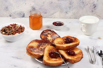 French toasts and granola on a gray table with breadcrumbs. Fried bread with milk and scrambled eggs. . Minimal concept of a modern bakery. Healthy traditional french breakfast.