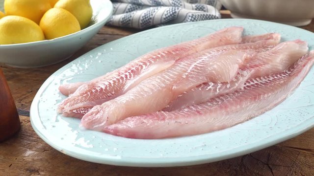 Fresh haddock fillets on a platter to be seasoned for cooking.
