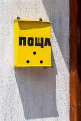 Yellow painted letterbox in Kazanlak, Stara Zagora Province, Bulgaria with the inscription Post in cyrillic script