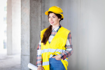 Portrait of a smiling young woman builder with drawings in hand
