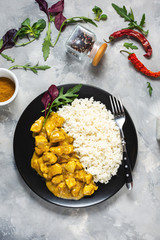 Rice with chicken in curry sauce on a plate on concrete background