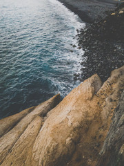 Toned image of black sand ocean beach and calm blue waves