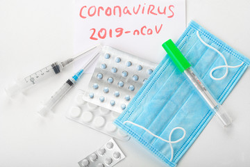 Different pills, syringes, text CORONAVIRUS. 2019 nCoV coronavirus on white background.