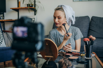 Young woman filming her make up routine. Young social media influencer filming her make up routine