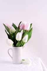Bunch ofwhite and pink tulips in a white vase on white table