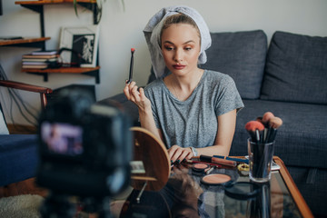 Obraz na płótnie Canvas Young woman filming her make up routine. Young social media influencer filming her make up routine