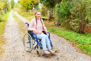 Young happy handicap woman in wheelchair on road in hospital park waiting for patient services....