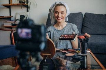 Fototapeta na wymiar Young woman showing her make up palette. Young social media influencer filming her make up routine