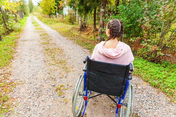 Young happy handicap woman in wheelchair on road in hospital park waiting for patient services....