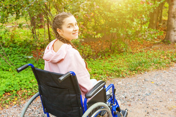 Young happy handicap woman in wheelchair on road in hospital park waiting for patient services....