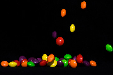 Many sweet and colourful candies are falling down to the table