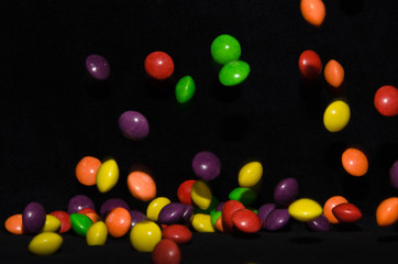 Many sweet and colourful candies are falling down to the table