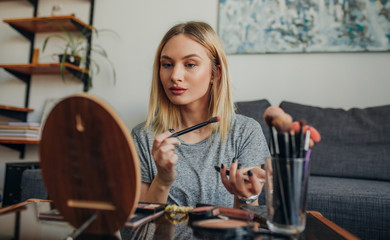 Young woman in her apartment doing her make up