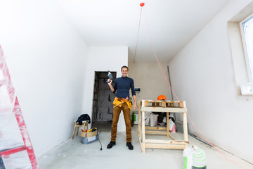 Home repair. Male hands using an electric perforator drill with a drill make a hole in the wall...