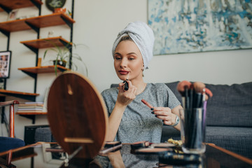 Young woman in her apartment doing her make up