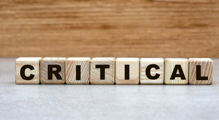 the concept of the word critical on cubes on a light wooden background