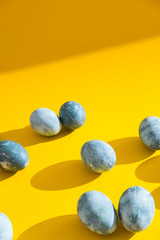 Blue textured colored Easter eggs on a bright yellow holiday background backdrop. Spring holiday concept. Copyspace. Flat lay. Top view.