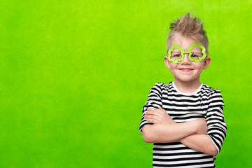 Little smiling caucasian boy in mask of leprechaun shamrock clover glasses for irish St. Patrick's...