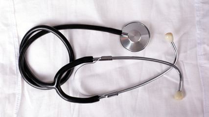 black stethoscope on a white medical gown closeup top view
