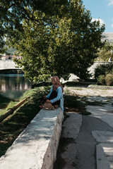 Fototapeta na wymiar Woman with hijab sitting and looking at beautiful old city of Trebinje and Trebisnjica river, Bosnia and Herzegovina. Reflections of city on river. September, 2018.