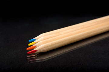 Obraz premium Multi-colored wooden pencils. Dark black background. Natural materials. Stationery. Office tools. Back to school. Education and art. Free space for text.
