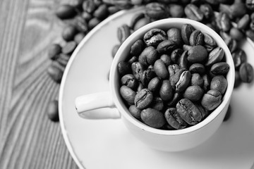 Black and white tint. An espresso cup filled with coffee beans.